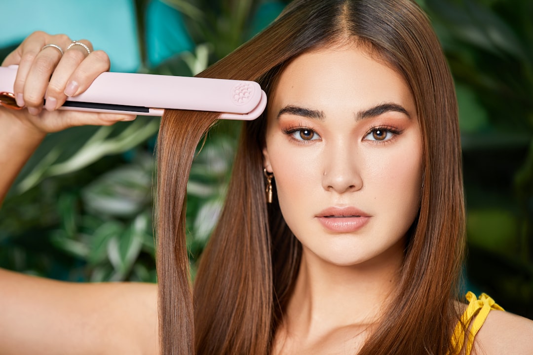 A woman gracefully styles her sleek hair with a TYMO Hair Flat Iron, framed by a lush.