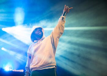 A rap singer holding a mic and pointing the crowd during a concert