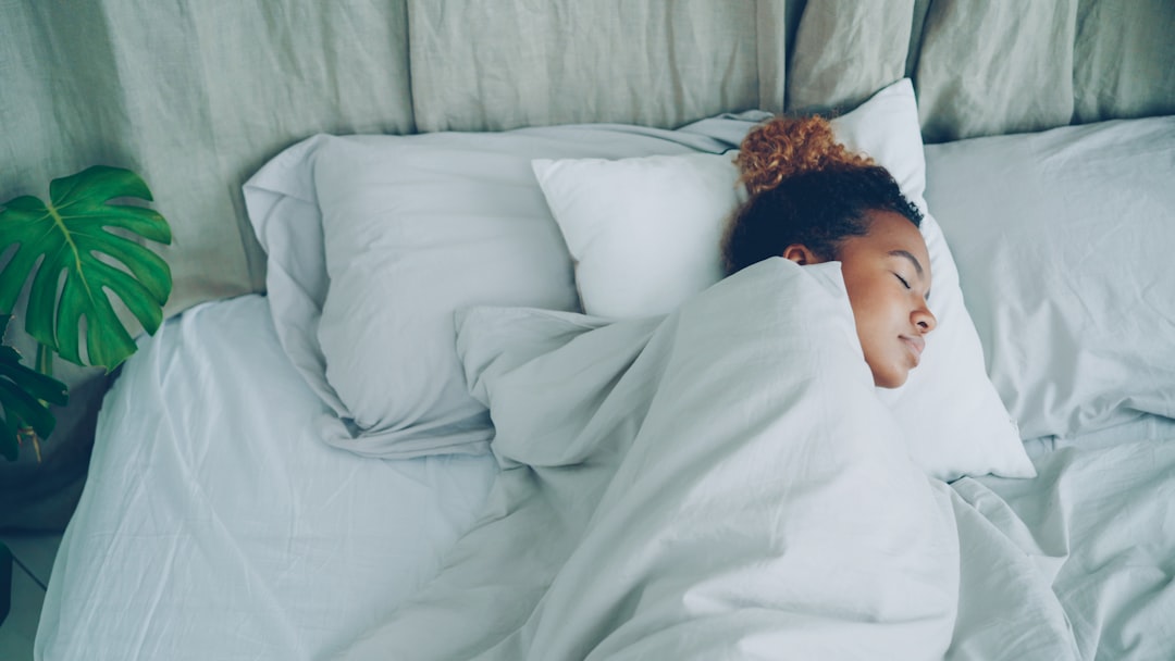 Young African American woman is sleeping in comfortable bed under warm blanket having rest on beautiful linen. Comfort, resting people and bedroom concept.